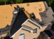 Crew removing asphalt shingles during full roof replacement on Texas home